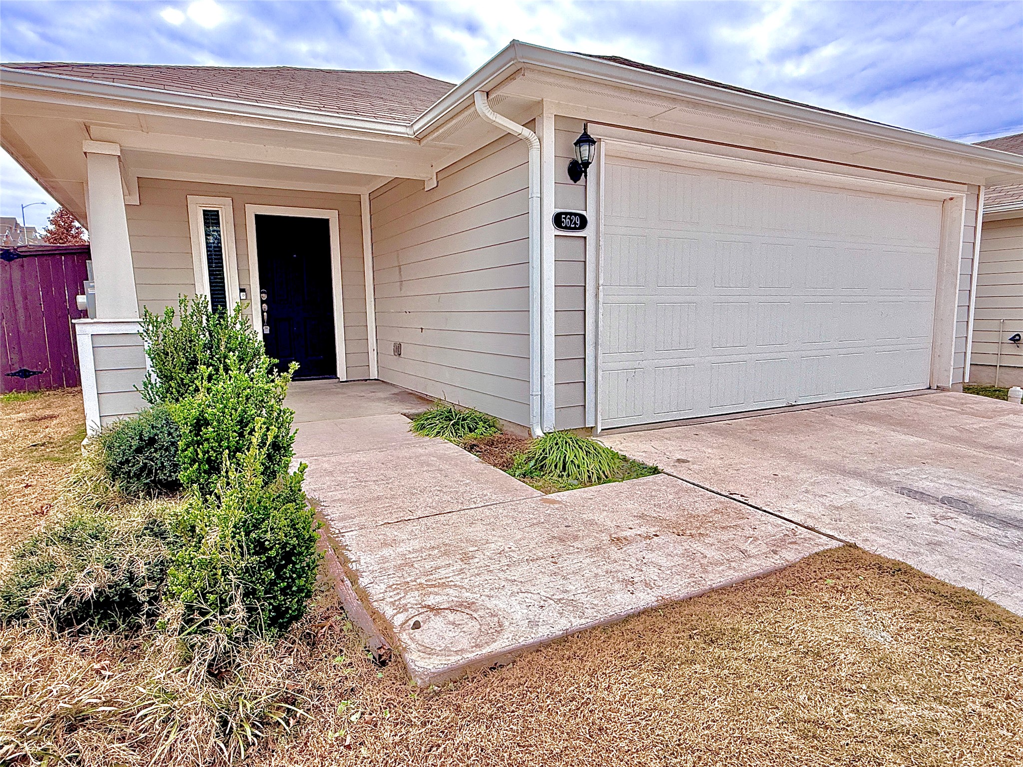 5629 Corso Court Austin, TX 78747 - Photo 2 of 23 View of front of property with concrete driveway, a shingled roof, an attached garage, and covered porch