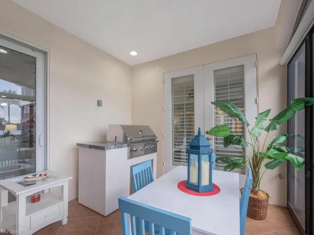 a kitchen with stainless steel appliances a dining table a stove a chimney a potted plant and a window