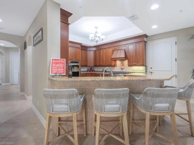 a kitchen with granite countertop a stove a cabinets and chairs