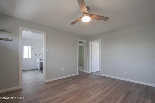 a view of an empty room with wooden floor and a window