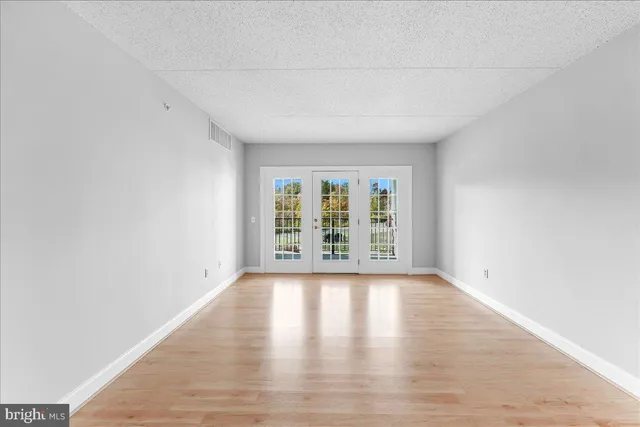 a view of an empty room with wooden floor and a window