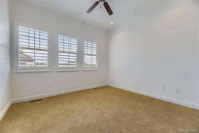 an empty room with ceiling fan and window