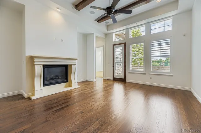 an empty room with wooden floor fireplace and windows