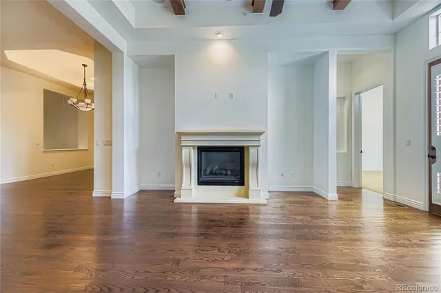 a view of an empty room with wooden floor and a fireplace