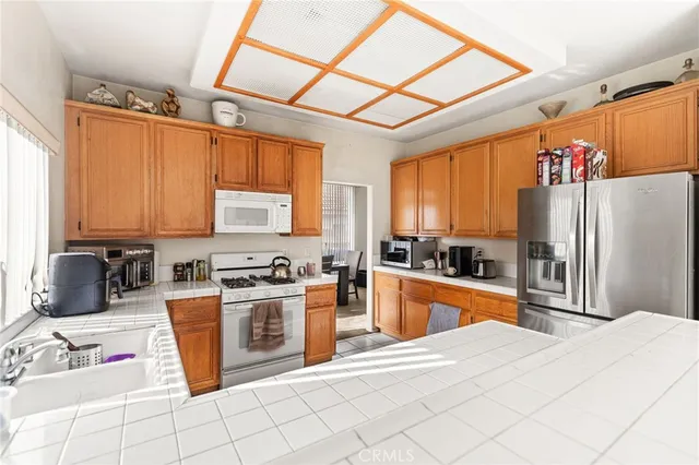 a kitchen with stainless steel appliances granite countertop a stove top oven a refrigerator a sink and dishwasher with wooden floor