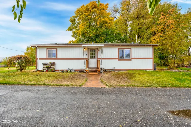 a view of a house with a yard and large trees