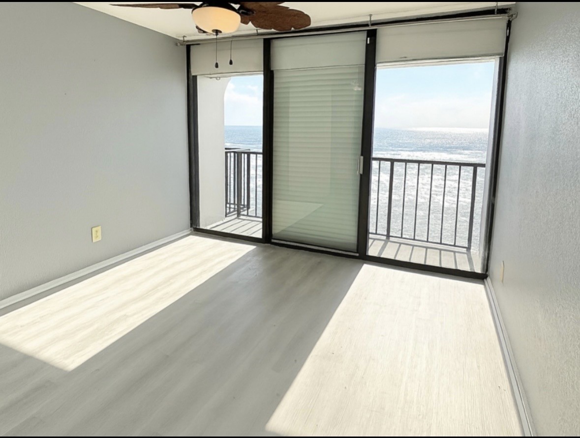 11949 Termini-San Luis Pass Road, Unit 603 Galveston, TX 77554 - Photo 7 of 9 a view of an empty room with wooden floor and a window