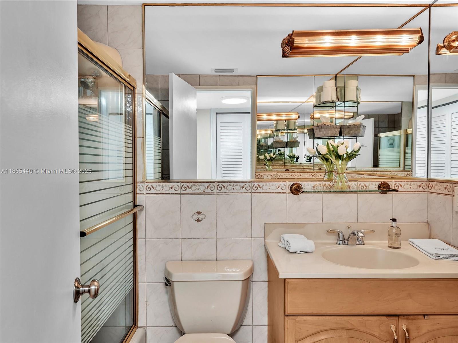 301 Sunrise Drive, Unit 1DW Key Biscayne, FL 33149 - Photo 13 of 40 a bathroom with a toilet a sink and mirror