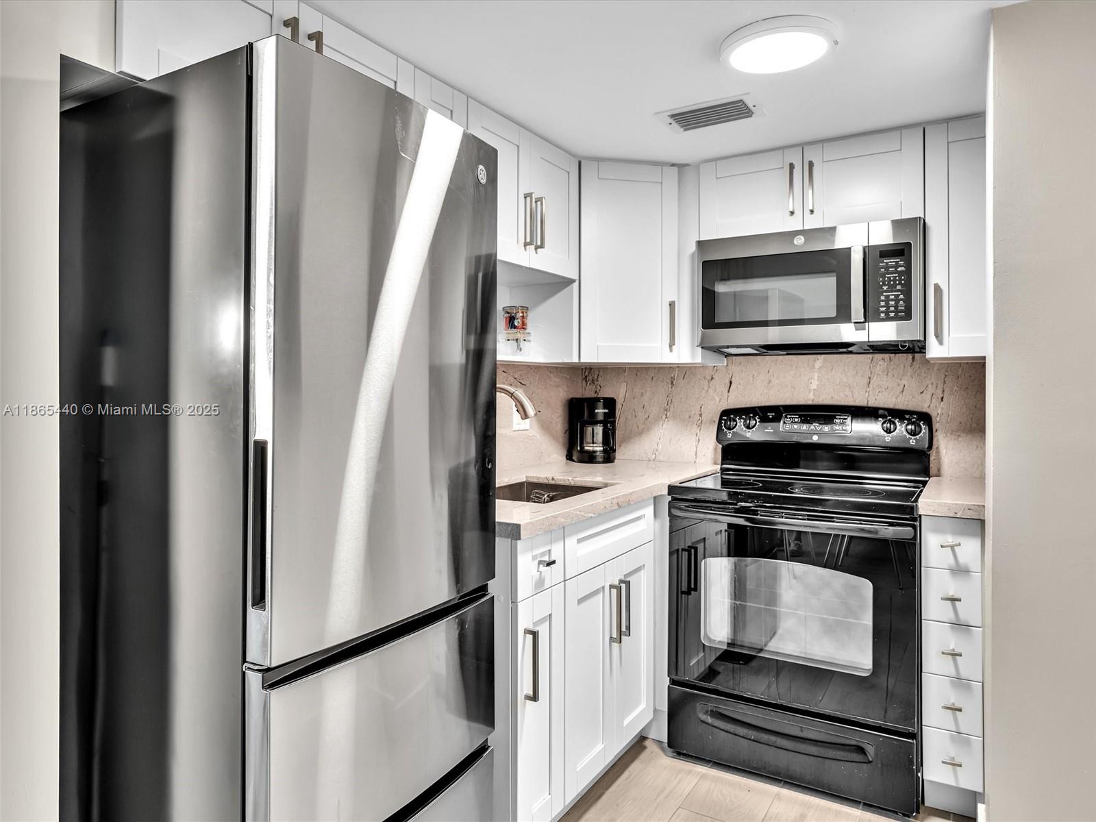 301 Sunrise Drive, Unit 1DW Key Biscayne, FL 33149 - Photo 6 of 40 a kitchen with stainless steel appliances a refrigerator stove and microwave