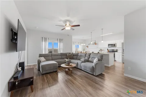 a living room with furniture kitchen view and a wooden floor