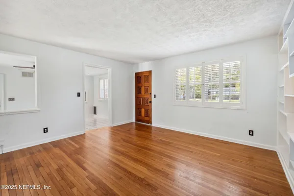 a view of empty room with wooden floor and fan