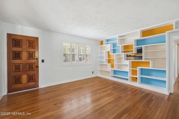 a view of empty room with wooden floor and window