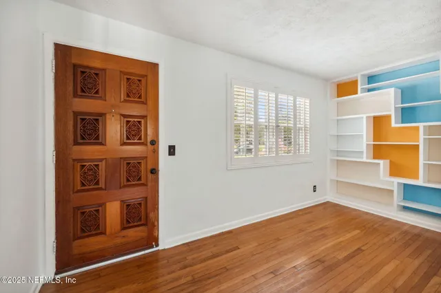 a view of empty room with wooden floor and windows