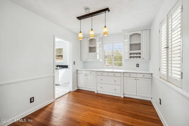an empty room with wooden floor cabinet and windows