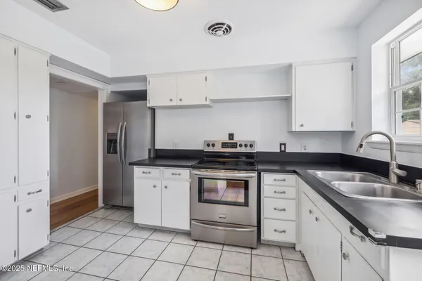 a kitchen with granite countertop white cabinets and appliances