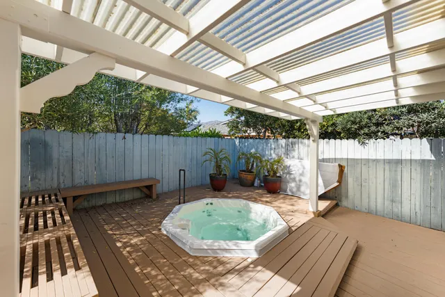 a view of a backyard with table and chairs potted plants with wooden floor and fence
