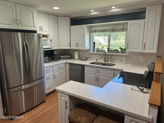 a kitchen with a refrigerator a sink dishwasher and a stove with wooden floor