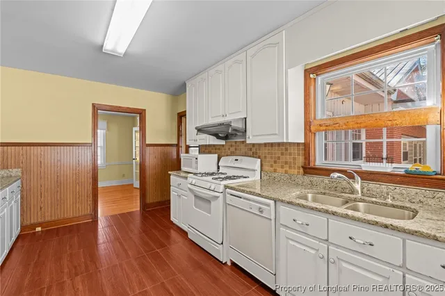 a kitchen with granite countertop wooden floors and white stainless steel appliances