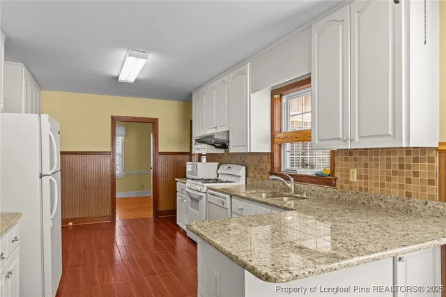 a kitchen with stainless steel appliances granite countertop a sink dishwasher and a refrigerator with wooden floor