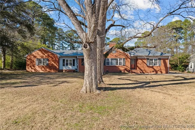 a view of a house with large trees and covered with snow