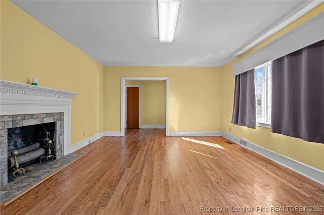 a view of an empty room with window and fire place
