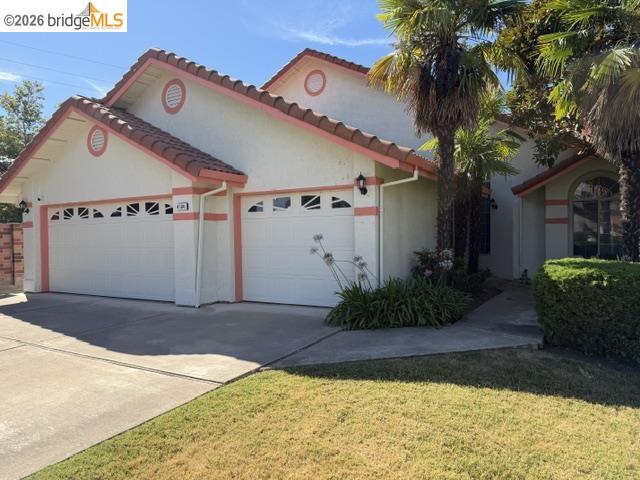 Stucco exterior with terracotta-style roof tiles, multiple palm trees, and an attached two-car garage