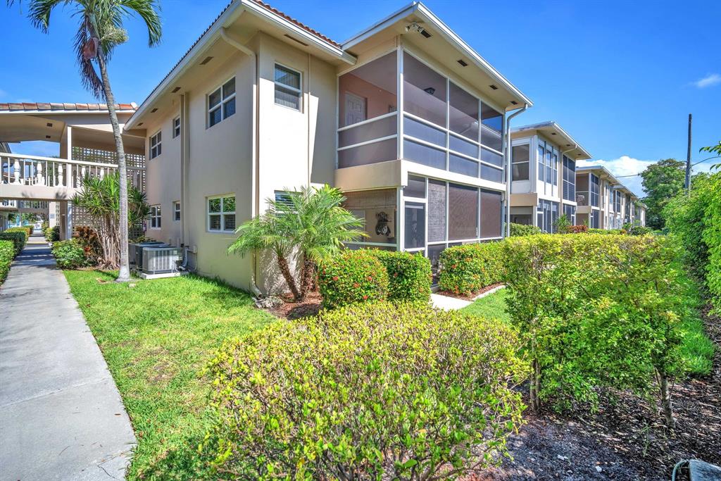 a view of a brick house with a yard and plants