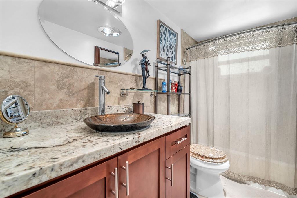 2131 Northeast 42nd Court, Unit 104E Lighthouse Point, FL 33064 - Photo 12 of 31 a bathroom with a granite countertop sink a toilet and a mirror