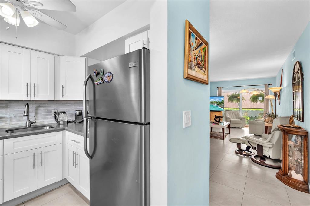 2131 Northeast 42nd Court, Unit 104E Lighthouse Point, FL 33064 - Photo 14 of 31 a white refrigerator freezer sitting in a kitchen with white cabinets and wooden floor