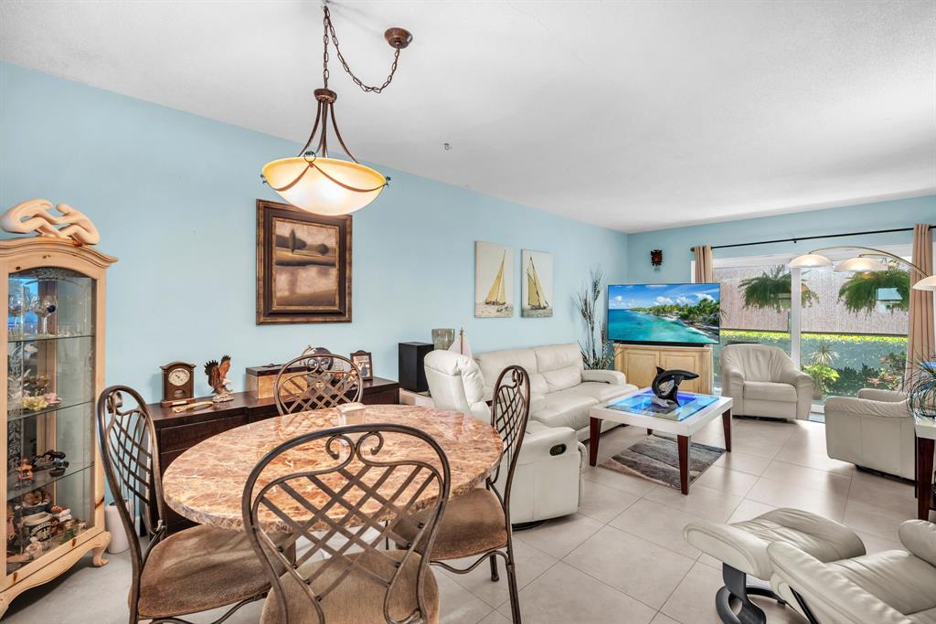 2131 Northeast 42nd Court, Unit 104E Lighthouse Point, FL 33064 - Photo 16 of 31 a living room with furniture a rug and a chandelier
