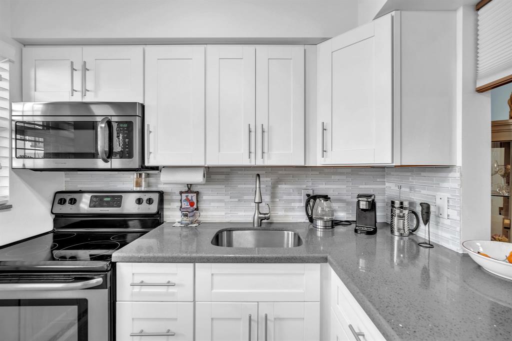2131 Northeast 42nd Court, Unit 104E Lighthouse Point, FL 33064 - Photo 18 of 31 a kitchen with stainless steel appliances granite countertop a sink stove and microwave