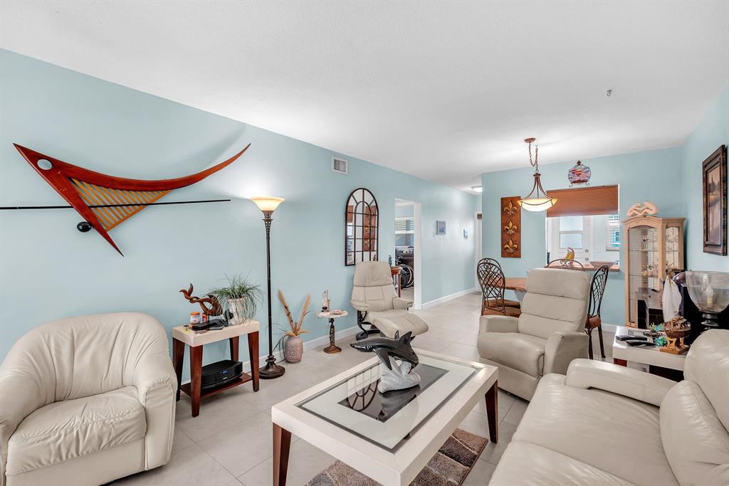 2131 Northeast 42nd Court, Unit 104E Lighthouse Point, FL 33064 - Photo 22 of 31 a living room with furniture a rug and a chandelier