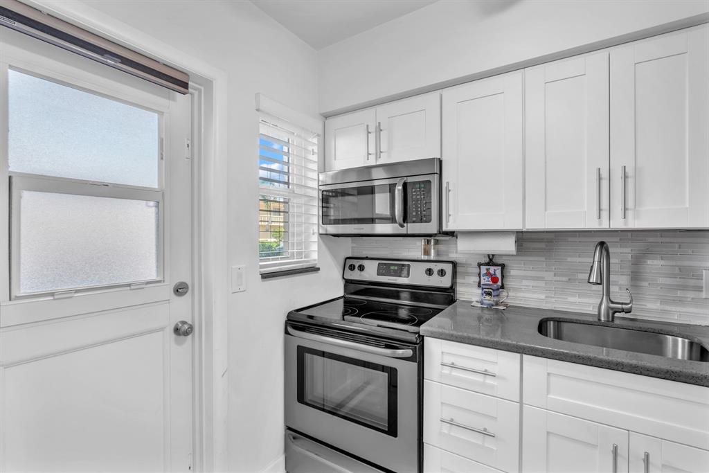 2131 Northeast 42nd Court, Unit 104E Lighthouse Point, FL 33064 - Photo 9 of 31 a kitchen with stainless steel appliances granite countertop white cabinets and a sink
