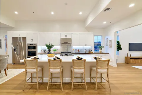 a kitchen with stainless steel appliances kitchen island granite countertop a dining table chairs and a refrigerator