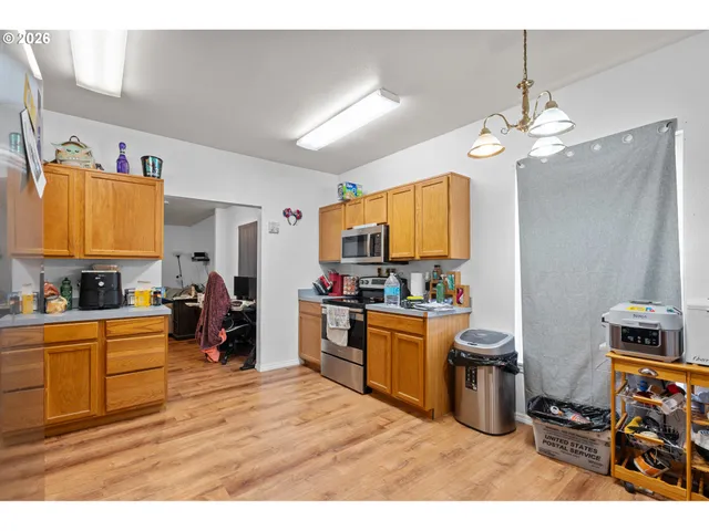 a kitchen with stainless steel appliances granite countertop a sink dishwasher a stove a dining table and chairs with wooden floor