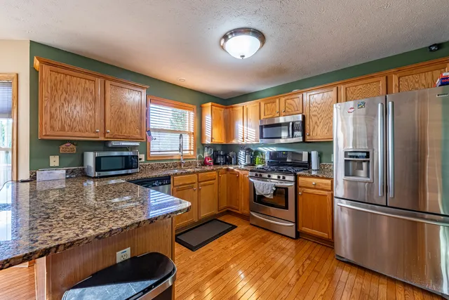 a kitchen with stainless steel appliances granite countertop a refrigerator a stove top oven a sink and dishwasher