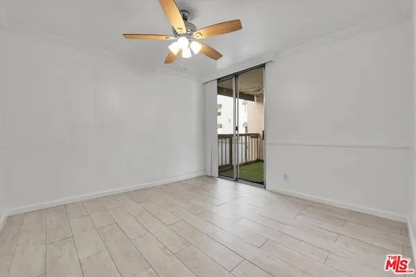 an empty room with wooden floor fan and windows