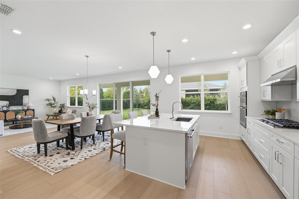 2430 Park Ridge Street Apopka, FL 32712 - Photo 14 of 49 a large kitchen with kitchen island granite countertop a stove a sink a dining table and chairs with wooden floor