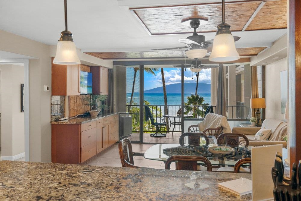 4327 Lower Honoapiilani Road, Unit 403 Lahaina, HI 96761 - Photo 10 of 42 a living room with furniture a chandelier and a dining table