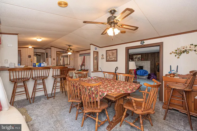 a dining hall with stainless steel appliances kitchen island granite countertop a sink and chairs