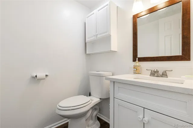 a bathroom with a toilet sink vanity and mirror