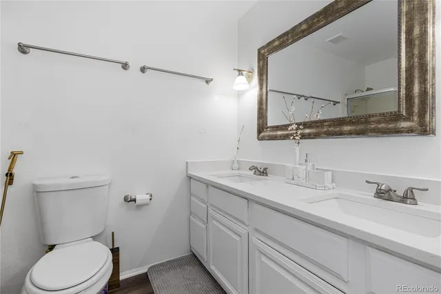 a bathroom with a granite countertop toilet sink and mirror