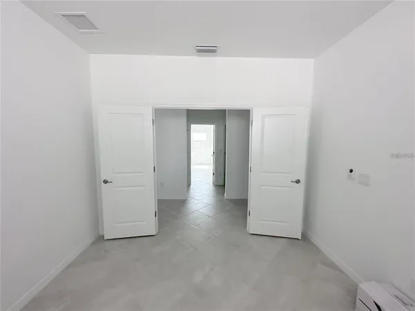 an empty room with ceiling fan and windows