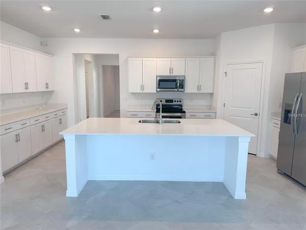 a view of an empty room with a window and kitchen view