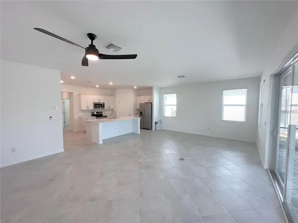 a large white kitchen with a refrigerator a stove top oven and white cabinets