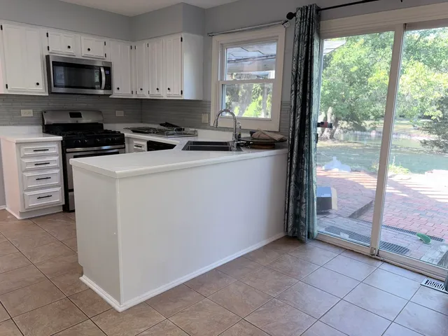 a kitchen with stainless steel appliances a sink a stove a refrigerator a sink and cabinets