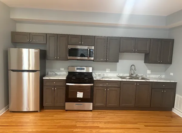 a kitchen with granite countertop a refrigerator and a stove top oven