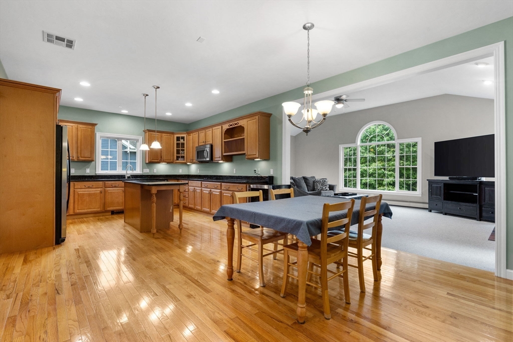 731 Samuel Drive Northbridge, MA 01588 - Photo 3 of 33 a kitchen with stainless steel appliances granite countertop a stove top oven a refrigerator a dining table and chairs with wooden floor