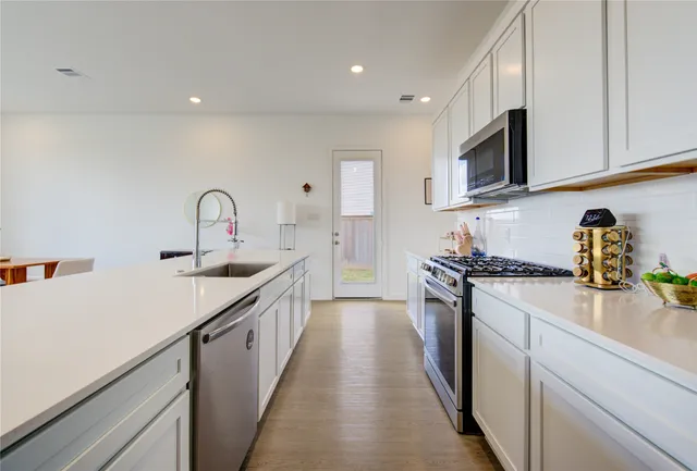 a kitchen with kitchen island granite countertop a sink and a stove top oven with wooden floor
