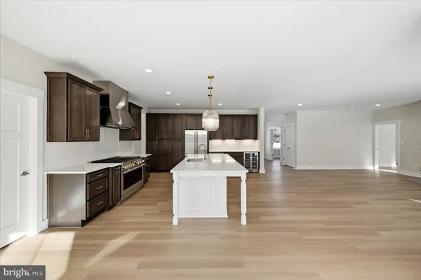 a large white kitchen with stainless steel appliances granite countertop a stove and a wooden floors
